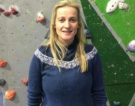 Jo standing in front of a climbing wall